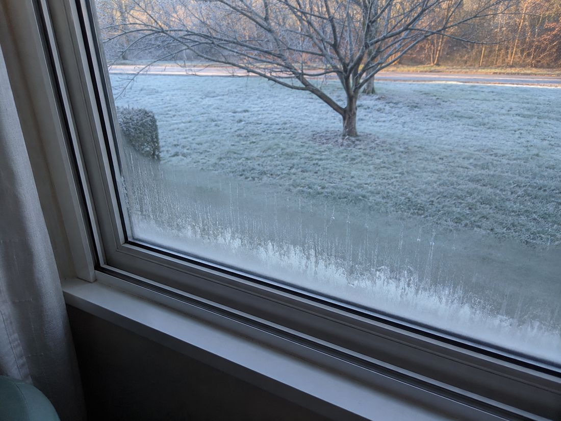 Condensation across the inside of a window on a Dunedin morning with frost on the lawn outside